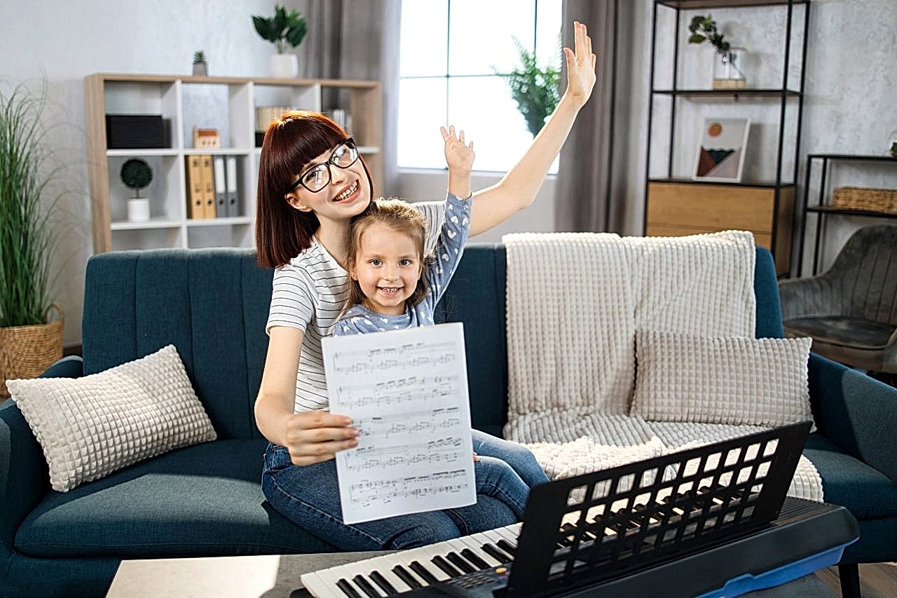 Mother teaching playing piano using notes her daughter.