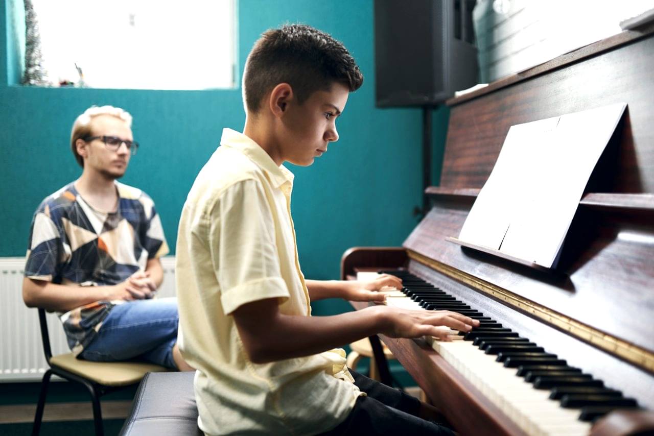 Piano teacher with a student playing the piano at lesson
